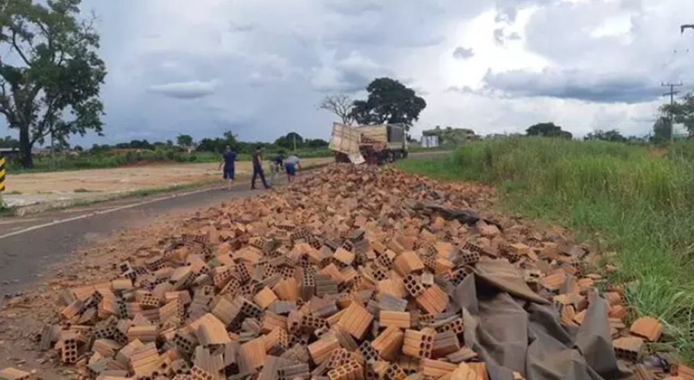 Carroceria de carreta abre e carga de tijolos fica espalhada em rodovia