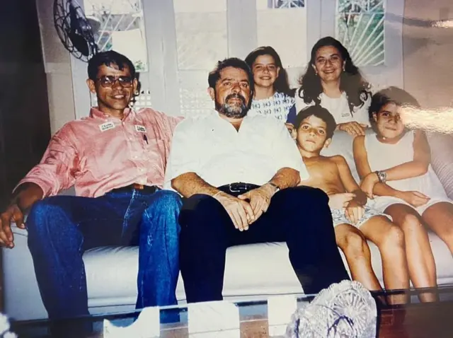 Fonteles aparece criança ao lado de Lula sentado no sofá em foto antiga. Imagem ainda tem pai de Fonteles, Nazareno, ao lado de Lula, e outras crianças.